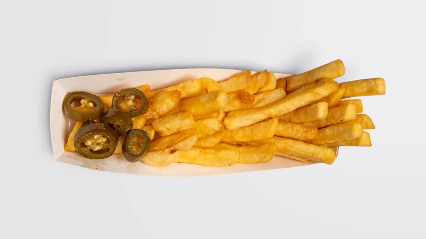 Fries and sliced jalapeños in a cardboard tray on a light background