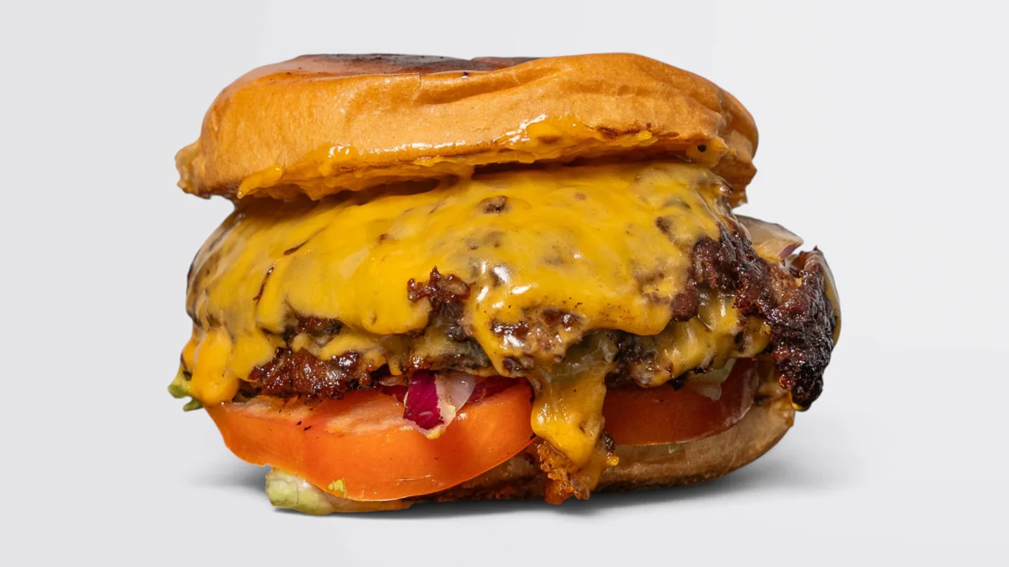 Gingerhead burger with melted cheese, tomato and red onion on a light background